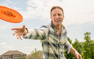 Man playing Frisbee outside of new home in Katy, Texas at Elyson community