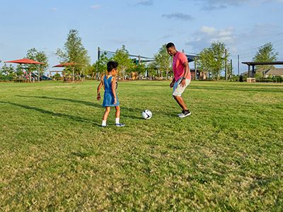 Residents playing soccer in great lawn at Elyson community, Katy, Texas
