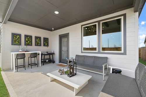 overed outdoor living space in a new Brookfield Residential home at Elyson in Katy, TX with seating area and bar height table
