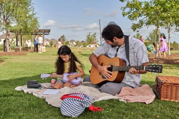 Father and daughter playing the guitar at Elyson Commons Elyson Katy, Tx