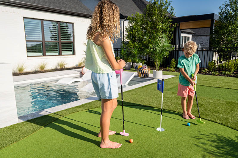 two kids practicing putting in back yard