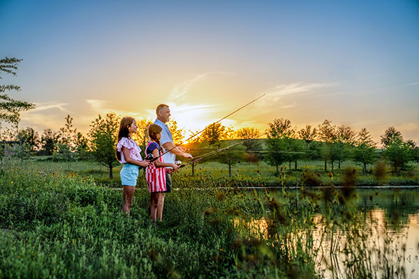 Family Fishing In Pond At Park
