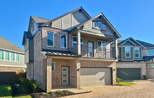 New homes in Katy TX under $400k at Elyson, three-story paired home with brick and gray siding, second-floor balcony, and two-car garage